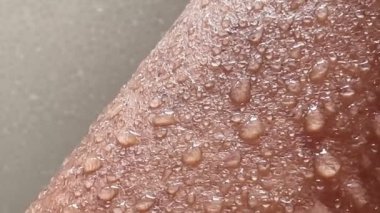 Islak bronzlaşmış bir vücuda 4K damla su. Bir el.
