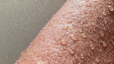 Islak bronzlaşmış bir vücuda 4K damla su. Bir el.