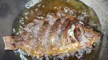 4K Chef müşterilere hizmet etmek için kızgın yağda tilapia kızartıyor. Tayland Sokak Yemekleri