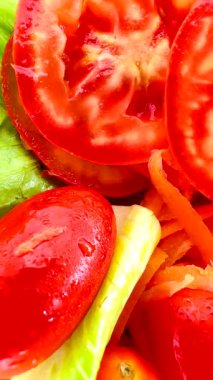 İnce dilimlenmiş havuç, kiraz domatesleri, dilimlenmiş kırmızı domates, yeşil (muhtemelen romaine marulu) ve dilimlenmiş sarı dolma biberli parlak ve taze bir salata. Dokuları çok farklı..