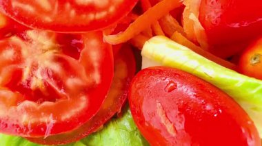 İnce dilimlenmiş havuç, kiraz domatesleri, dilimlenmiş kırmızı domates, yeşil (muhtemelen romaine marulu) ve dilimlenmiş sarı dolma biberli parlak ve taze bir salata. Dokuları çok farklı..