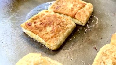 4k Street yiyecek satıcısı hamur ve tavada kızartılmış paratha roti 'yi dışarıda çıtır çıtır olana kadar kızgın yağda hazırlıyor. Sokak işportacısı sabah kahvaltısı için prata ekmeği veya roti canai hazırlıyor.