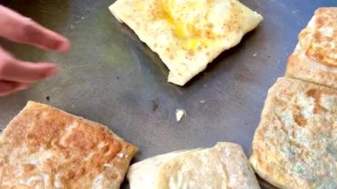 4k Street yiyecek satıcısı hamur ve tavada kızartılmış paratha roti 'yi dışarıda çıtır çıtır olana kadar kızgın yağda hazırlıyor. Sokak işportacısı sabah kahvaltısı için prata ekmeği veya roti canai hazırlıyor.