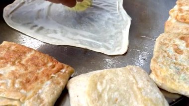 4k Street yiyecek satıcısı hamur ve tavada kızartılmış paratha roti 'yi dışarıda çıtır çıtır olana kadar kızgın yağda hazırlıyor. Sokak işportacısı sabah kahvaltısı için prata ekmeği veya roti canai hazırlıyor.