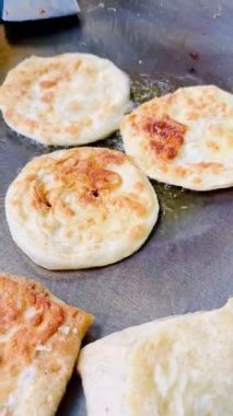 4k Street yiyecek satıcısı hamur ve tavada kızartılmış paratha roti 'yi dışarıda çıtır çıtır olana kadar kızgın yağda hazırlıyor. Sokak işportacısı sabah kahvaltısı için prata ekmeği veya roti canai hazırlıyor.