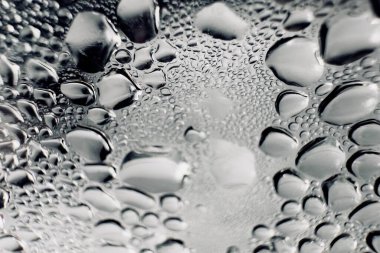 Metal yüzeydeki su damlacıklarının yoğunlaşmasını gösteren yüksek çözünürlüklü su damlalarının yakın çekim görüntüsü. Karmaşık desenler ve farklı boyutlardaki su damlacıkları güzel bir soyut doku oluşturur.. 