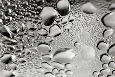 Metal yüzeydeki su damlacıklarının yoğunlaşmasını gösteren yüksek çözünürlüklü su damlalarının yakın çekim görüntüsü. Karmaşık desenler ve farklı boyutlardaki su damlacıkları güzel bir soyut doku oluşturur.. 
