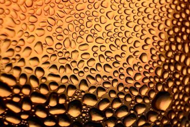 Metal yüzeydeki su damlacıklarının yoğunlaşmasını gösteren yüksek çözünürlüklü su damlalarının yakın çekim görüntüsü. Karmaşık desenler ve farklı boyutlardaki su damlacıkları güzel bir soyut doku oluşturur.. 