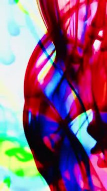 Suya renkli mürekkeplerle akan canlı renklere sahip soyut video. Kompozisyon mavi, kırmızı, yeşil ve sarı tonlarından oluşur. Hafif bir arkaplanda harmanlanır ve kıvrılır.