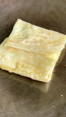 4k Street yiyecek satıcısı hamur ve tavada kızartılmış paratha roti 'yi dışarıda çıtır çıtır olana kadar kızgın yağda hazırlıyor. Sokak işportacısı sabah kahvaltısı için prata ekmeği veya roti canai hazırlıyor.