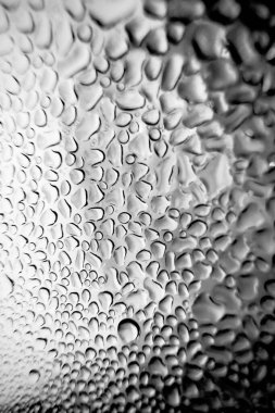 Metal yüzeydeki su damlacıklarının yoğunlaşmasını gösteren yüksek çözünürlüklü su damlalarının yakın çekim görüntüsü. Karmaşık desenler ve farklı boyutlarda su damlacıkları güzel bir soyut oluşturur.