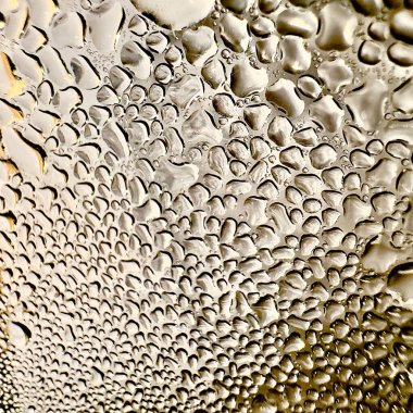 Metal yüzeydeki su damlacıklarının yoğunlaşmasını gösteren yüksek çözünürlüklü su damlalarının yakın çekim görüntüsü. Karmaşık desenler ve farklı boyutlarda su damlacıkları güzel bir soyut oluşturur.