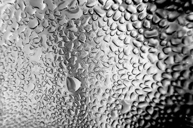 Metal yüzeydeki su damlacıklarının yoğunlaşmasını gösteren yüksek çözünürlüklü su damlalarının yakın çekim görüntüsü. Karmaşık desenler ve farklı boyutlarda su damlacıkları güzel bir soyut oluşturur.