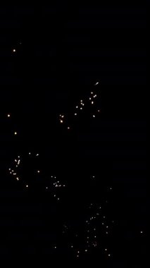 4 bin. Gerçek havai fişeklerin kusursuz döngü arka planında gece gökyüzünde Bokeh ışıkları olan altın havai fişekler. Parlak havai fişek gösterisi. Yeni yıl arifesinde havai fişekler gökyüzünde çeşitli renkleri kutluyor
