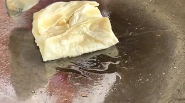 4k Street yiyecek satıcısı hamur ve tavada kızartılmış paratha roti 'yi dışarıda çıtır çıtır olana kadar kızgın yağda hazırlıyor. Sokak işportacısı sabah kahvaltısı için prata ekmeği veya roti canai hazırlıyor.