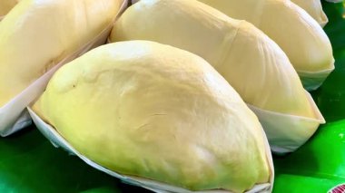 Yeşil bir muz yaprağına düzgünce yerleştirilmiş taze olgun durian parçaları var. Durian 'ın her parçası beyaz balmumu kağıdıyla dikkatlice altına sarılmış. En iyi Tayland meyvesi..