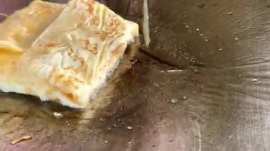 4k Street yiyecek satıcısı hamur ve tavada kızartılmış paratha roti 'yi dışarıda çıtır çıtır olana kadar kızgın yağda hazırlıyor. Sokak işportacısı sabah kahvaltısı için prata ekmeği veya roti canai hazırlıyor.