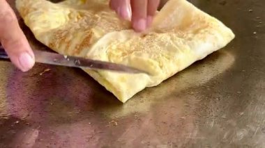 4k Street yiyecek satıcısı hamur ve tavada kızartılmış paratha roti 'yi dışarıda çıtır çıtır olana kadar kızgın yağda hazırlıyor. Sokak işportacısı sabah kahvaltısı için prata ekmeği veya roti canai hazırlıyor.
