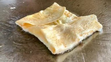 4k Street yiyecek satıcısı hamur ve tavada kızartılmış paratha roti 'yi dışarıda çıtır çıtır olana kadar kızgın yağda hazırlıyor. Sokak işportacısı sabah kahvaltısı için prata ekmeği veya roti canai hazırlıyor.