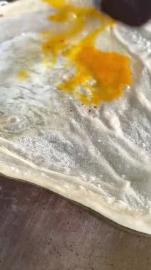 4k Street yiyecek satıcısı hamur ve tavada kızartılmış paratha roti 'yi dışarıda çıtır çıtır olana kadar kızgın yağda hazırlıyor. Sokak işportacısı sabah kahvaltısı için prata ekmeği veya roti canai hazırlıyor.
