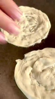 4k Street yiyecek satıcısı hamur ve tavada kızartılmış paratha roti 'yi dışarıda çıtır çıtır olana kadar kızgın yağda hazırlıyor. Sokak işportacısı sabah kahvaltısı için prata ekmeği veya roti canai hazırlıyor.
