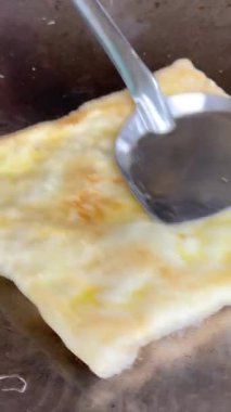 4k Street yiyecek satıcısı hamur ve tavada kızartılmış paratha roti 'yi dışarıda çıtır çıtır olana kadar kızgın yağda hazırlıyor. Sokak işportacısı sabah kahvaltısı için prata ekmeği veya roti canai hazırlıyor.