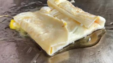 4k Street yiyecek satıcısı hamur ve tavada kızartılmış paratha roti 'yi dışarıda çıtır çıtır olana kadar kızgın yağda hazırlıyor. Sokak işportacısı sabah kahvaltısı için prata ekmeği veya roti canai hazırlıyor.