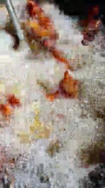  Şef kızgın yağda domuz kızartması yapıyor. En dikkat çekici nokta, metal bir spatula kullanarak kaynayan yağın yüzeyindeki altın-kahverengi domuz parçalarını kaldırmak. Bu da yüksek ısı ve cips olduğunu gösterir.