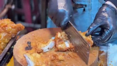 Ahşap kesme tahtasının üzerinde kızarmış tavuk doğrayan bir şefin yakın çekimi. Bangkok 'ta sokak yemeği.