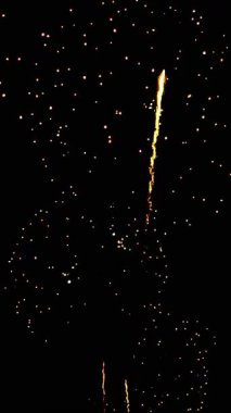 4 bin. Gerçek havai fişeklerin kusursuz döngü arka planında gece gökyüzünde Bokeh ışıkları olan altın havai fişekler. Parlak havai fişek gösterisi. Yeni yıl arifesinde havai fişekler birden fazla rengi kutluyor. 