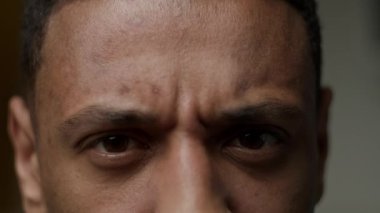 Kızgın siyah erkek gözleri. Afrikalı Amerikalı bir adamın yüzü kameraya negatif duygu gösteriyor. 4K