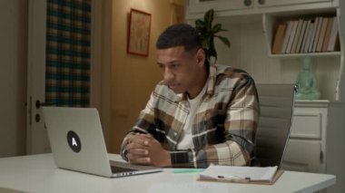 Yorgun adam dizüstü bilgisayar kullanıyor. Yorgun düşmüş Afrikalı Amerikalı adam işini evde bitirir. 4K