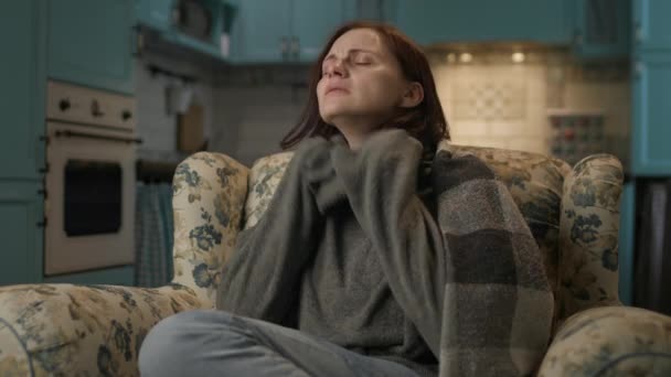 家で寒さを感じる女性 毛布に包まれた30代の女性はソファで暖まるために アパートで暖房がない — ストック動画