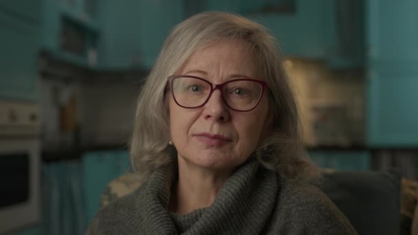 高齢女性の肖像画 カメラを見て微笑む眼鏡の熟女 自宅で年金生活者 — ストック動画