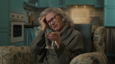 Yaşlı kadının başı ağrıyormuş. Son sınıf öğrencisi kadın evde oturmuş ilaç alıyor. Yaşlı kadın migrenden muzdarip. 4K