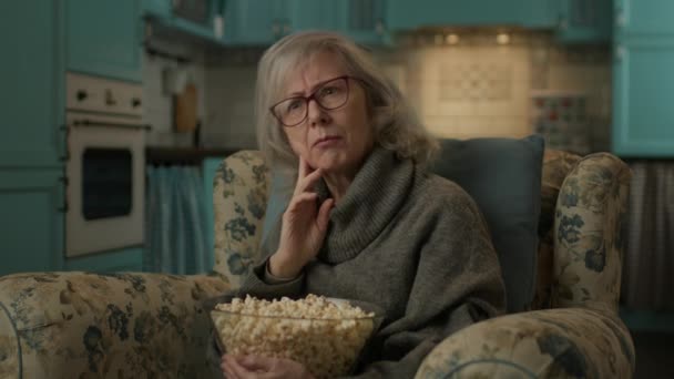 팝콘을 나이든 여성이 시청을 집에서 의자에 영화를 있습니다 — 비디오