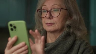 Kıdemli Kadın Akıllı Telefon Kullanarak Mesaj Yazıyor. Elinde cep telefonu tutan yaşlı bir kadın. Olgun insan yakın plan cihazlar kullanıyor. 4K