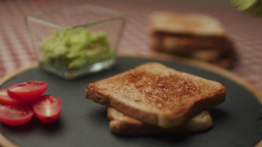Avokado tostun üzerine yayılıyor. Ekmeğin üstünde guacamole sosuyla el yapımı sağlıklı kahvaltı. 4K