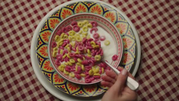 顶部视图混合玉米片和牛奶 将勺子放在有彩色玉米片环的碗里 — 图库视频影像