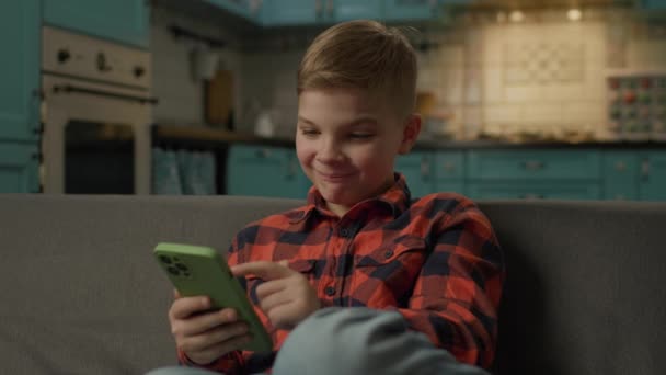 가정용 스마트폰을 사용하는 어린이 소파에 전화를 사용하여 인터넷을 검색하는 남자아이 — 비디오
