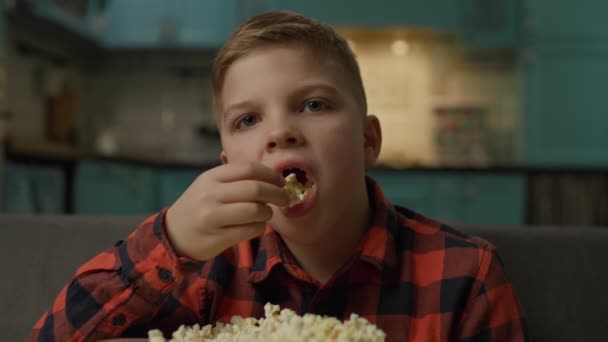 Dzieciak Jedzący Popcorn Patrzący Kamerę Chłopak Ogląda Telewizję Popcornem Kanapie — Wideo stockowe
