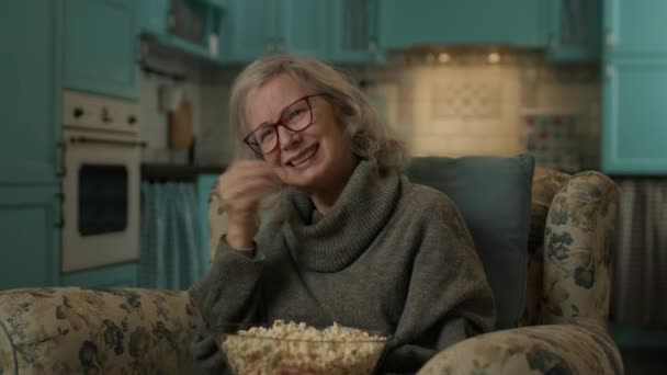 Starsza Kobieta Ogląda Telewizję Jedzącą Popcorn Tka Śmieje Się Oglądając — Wideo stockowe