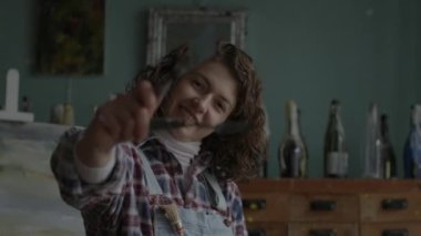 Artist Holding Brushes Portrait. Female painter in workshop. Woman smiling at camera in art space. 4K