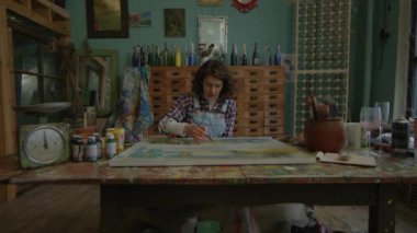 Ressam fırçayla şaheser yaratıyor. Kadın ressam atölyede oturuyor. Sanat atölyesinde çalışan bir kadın. 4K