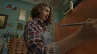 Ressam tuvalde resim yapıyor. Boyacı atölyede fırça kullanıyor. Sanat atölyesinde çalışan bir kadın. 4K
