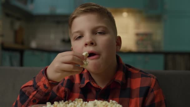 Child Eats Popcorn Looking Camera Boy Watching Popcorn Sitting Sofa — Stockvideo