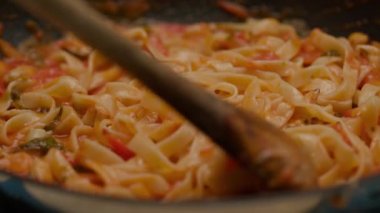 Mixing pasta with tomato sauce on frying pan in slow motion. 4K
