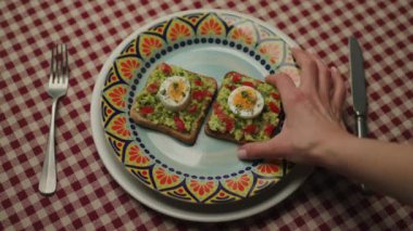 Avocado Toast In Hand Close Up. Person holding piece of bread with guacamole and egg. Healthy breakfast. 4K