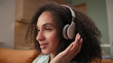 Kulaklıklı Kadın Müzik Dinliyor. Karışık ırk kadınları evde oturan kablosuz kulaklık takarak müzik dinlemeyi severler. 4K