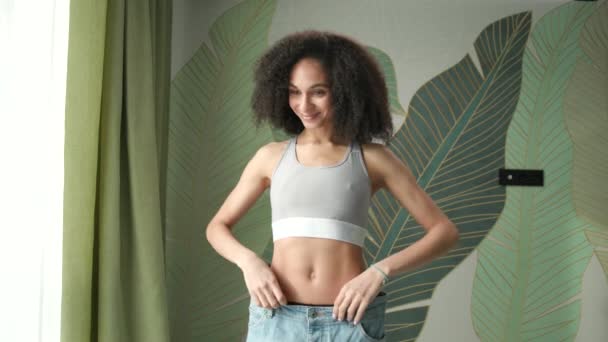 减肥后快乐的女人 混血的苗条女子穿着超大号牛仔裤 成功减肥 — 图库视频影像